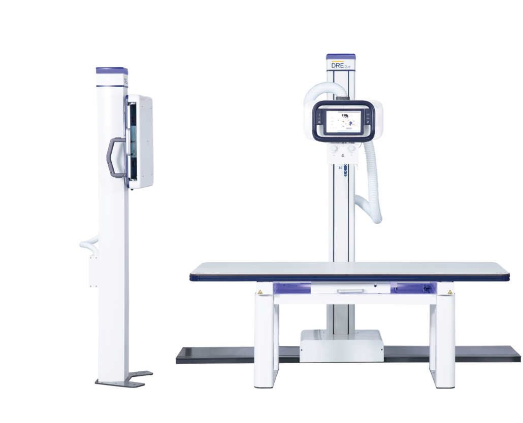 DRE Duo digital radiography X-ray system featuring a floor-mounted X-ray tube stand with integrated touchscreen display, an adjustable patient examination table, and a vertical wall bucky stand against a black background.